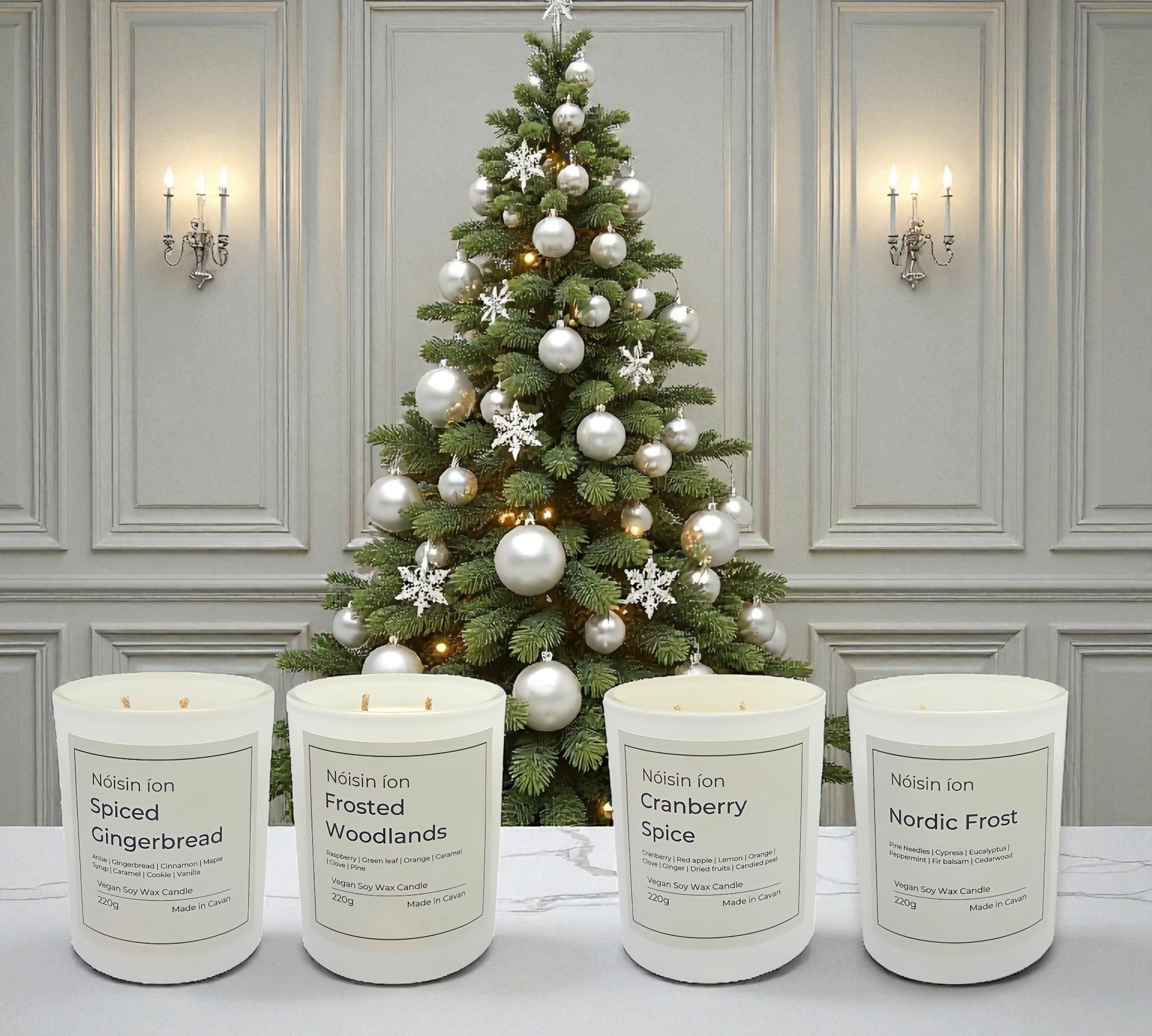 Four candles with labels in front of a decorated Christmas tree.