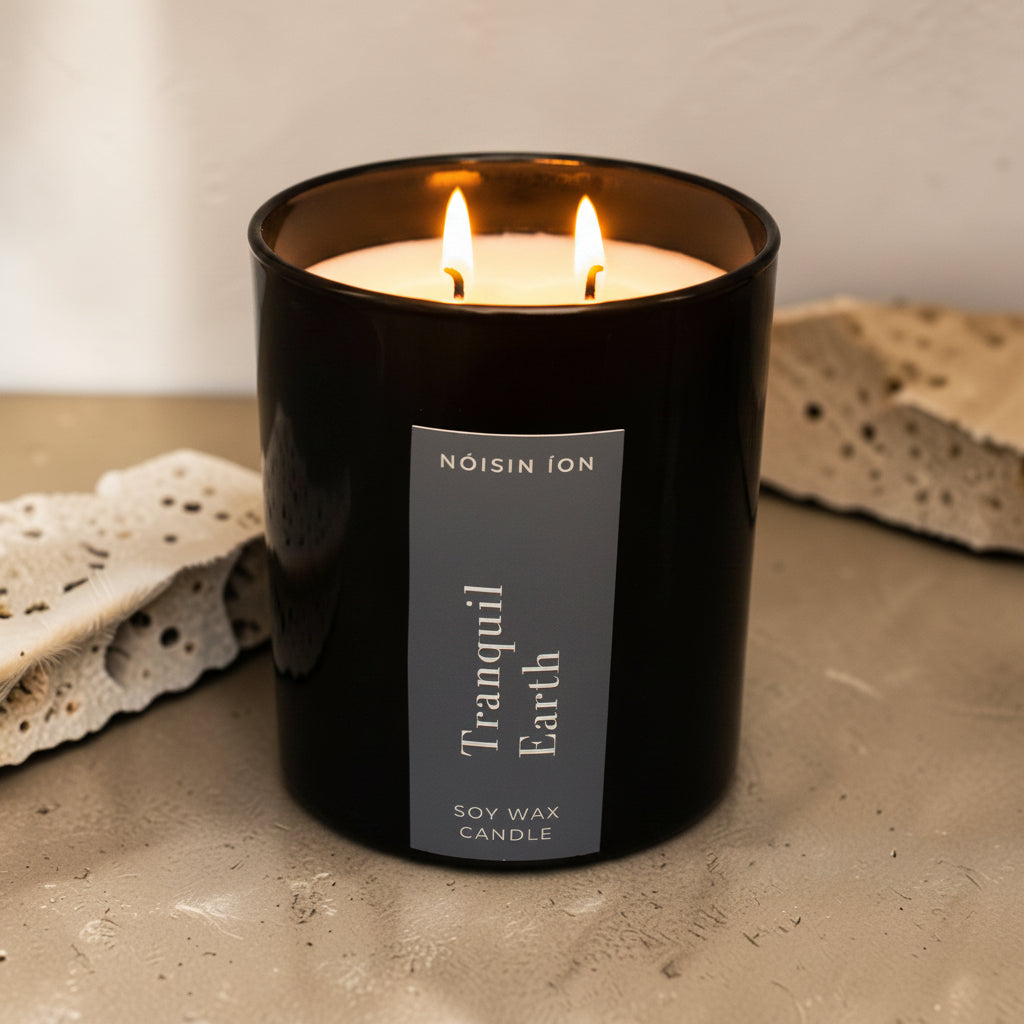 Lit Tranquil Earth luxury soy wax candle in a black gloss jar with a dark navy label by Nóisin Íon.