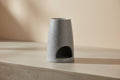Grey Wax Melter with a cylindrical shape on a concrete and beige background