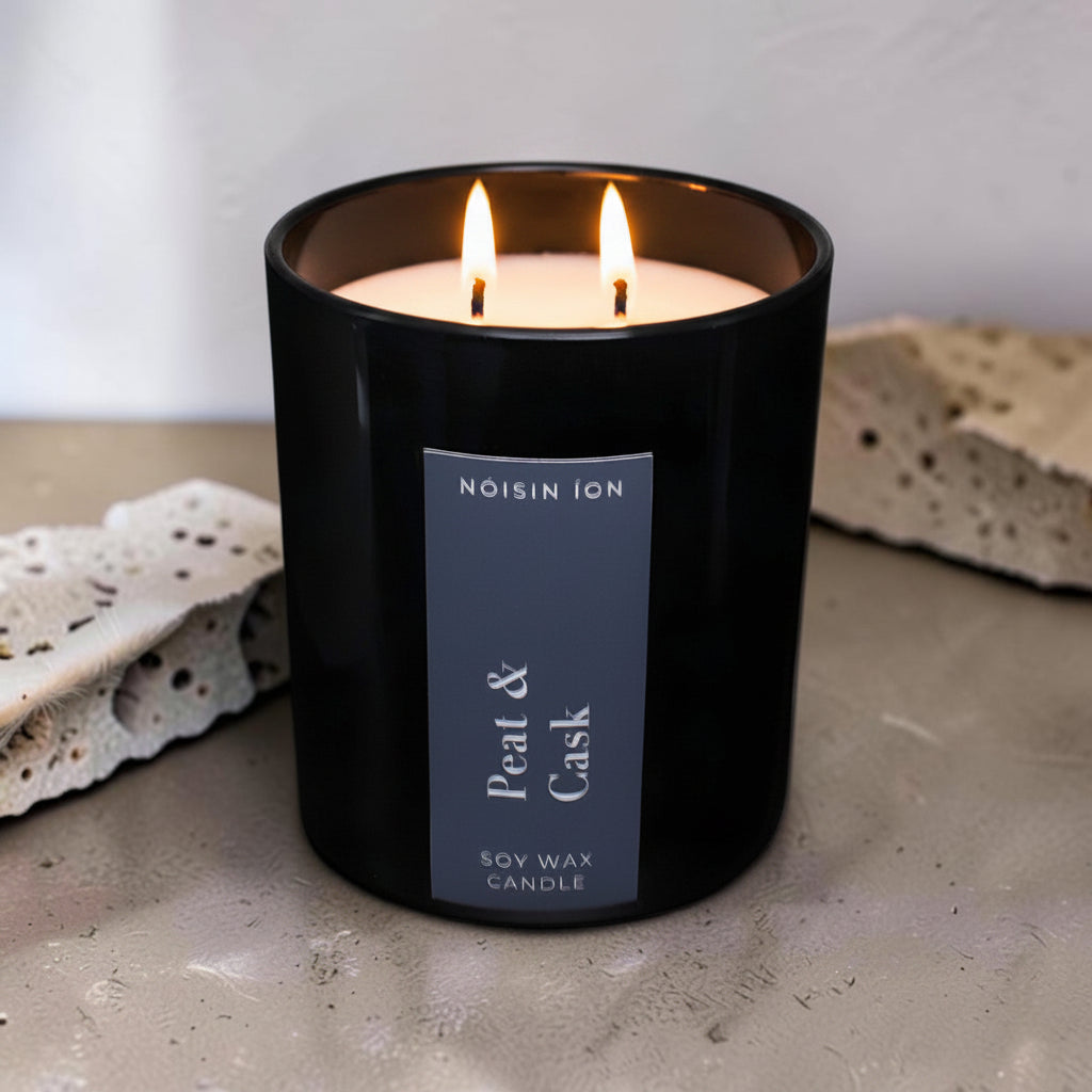 Lit Peat & Cask luxury soy wax candle in a black gloss jar with a dark navy label by Nóisin Íon.